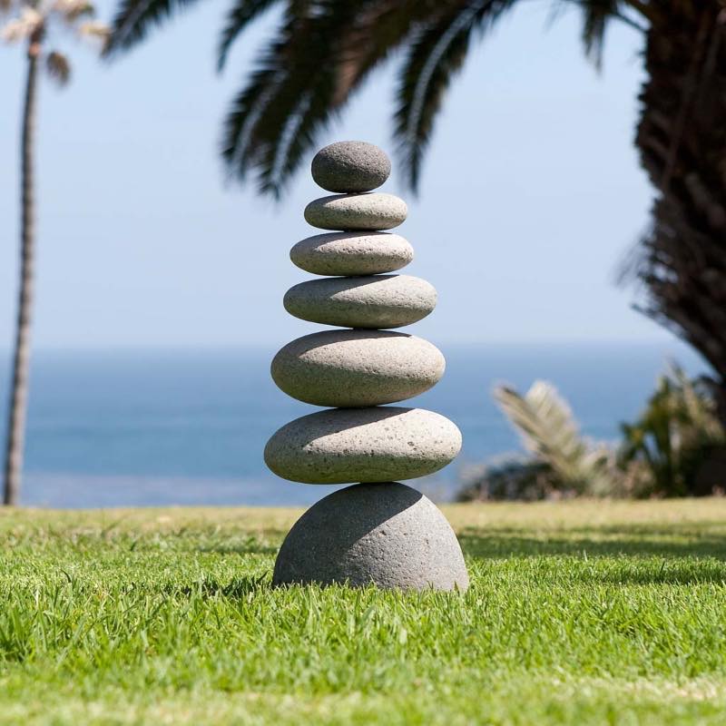 Balanced stone cairn surrounded by gentle grass and earth tones representing grounding and stability